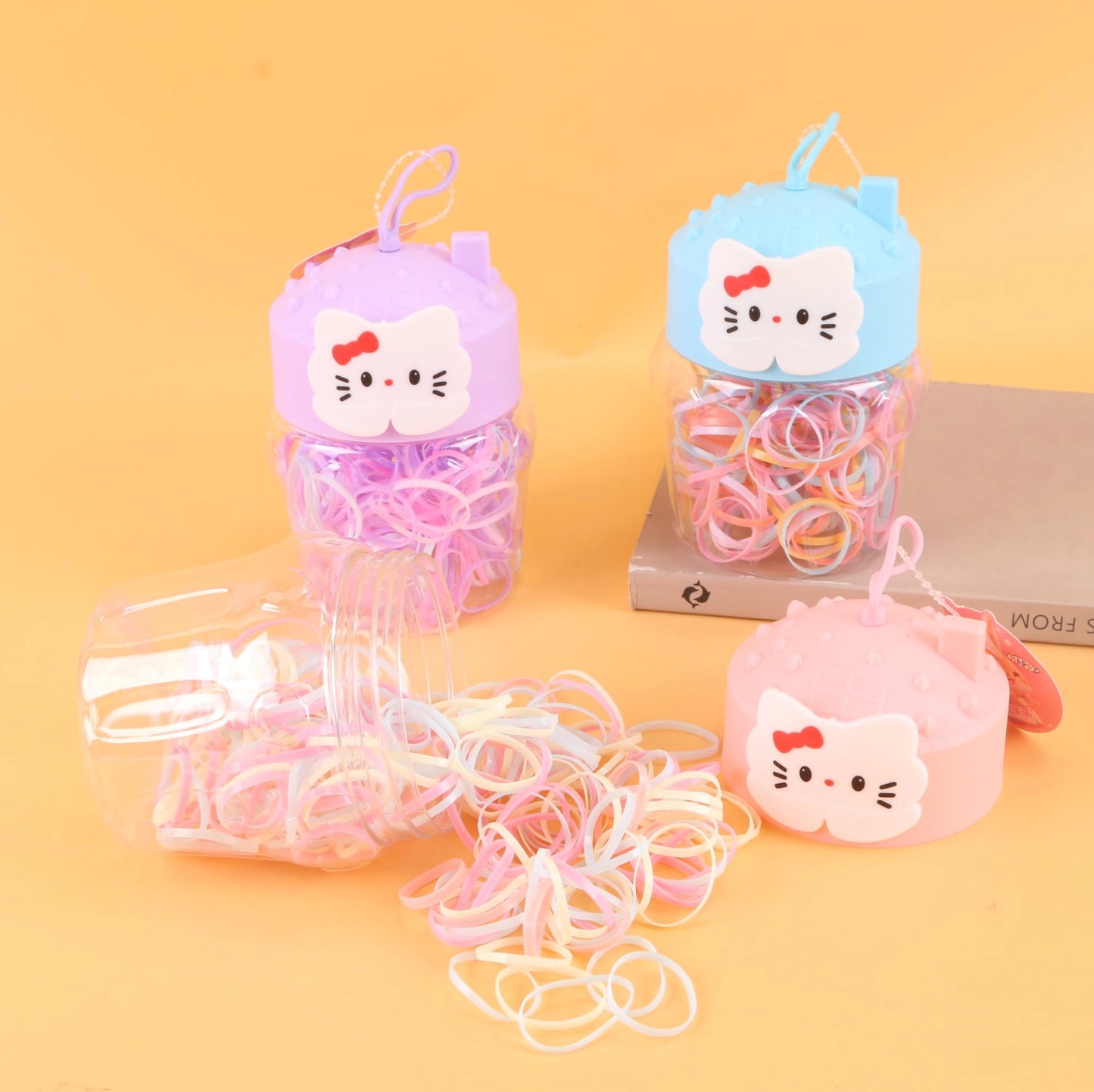 fondo tomate con  Ligas de colores desechables para cabello en frasco decorativo con tapa en forma de gato. Caja de 24, ideal para tiendas y mayoristas.