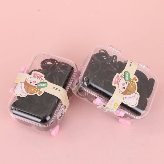 fondo rosa con Ligas elásticas negras presentadas en caja tipo maleta. Prácticas y resistentes. Ideal para mayoristas y tiendas de accesorios.