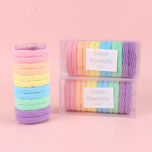 fondo rosa con Ligas elásticas de colores en caja larga tipo jacquard. Presentación ligera y práctica para mayoristas y tiendas de accesorios.