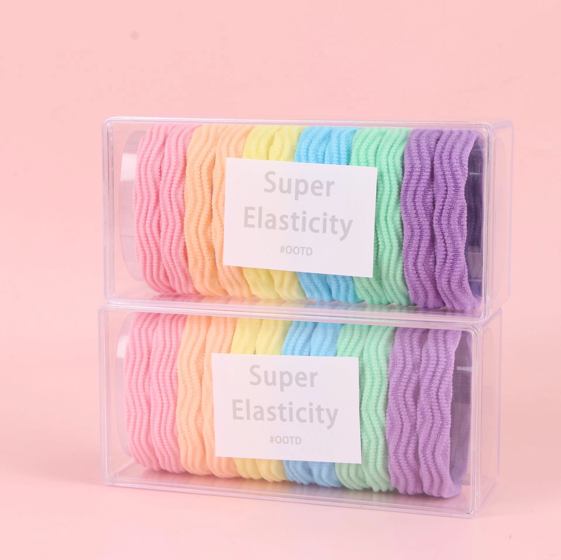 fondo rosa con 2 cajas de Ligas elásticas de colores en caja larga tipo jacquard. Presentación ligera y práctica para mayoristas y tiendas de accesorios.