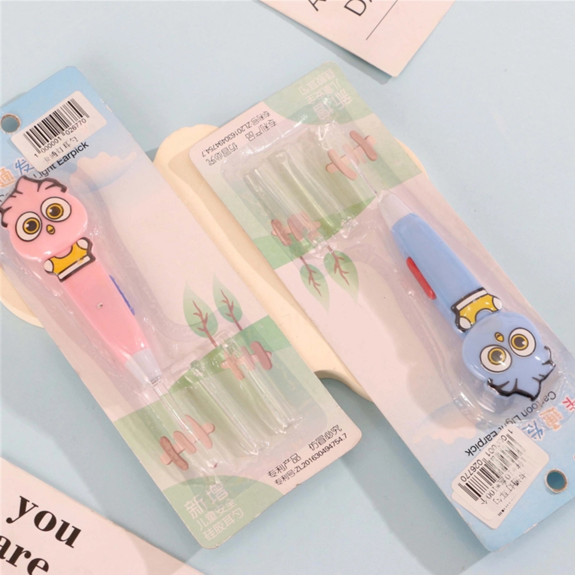 fondo celeste con dos sets de Palillo de oído con luz LED y diseño de dibujos animados.